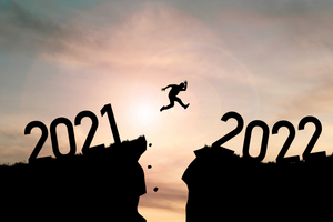 A man jumping from a cliff that says 2021 to an adjacent cliff that says 2022 (Success Through Failure episode 329: A Blueprint for Goal Setting for 2022)
