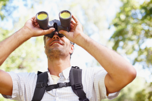 A man looking through a binoculars (Success Through Failure episode 348: How to Confidently Identify Your BHAG Even If You're Not Sure Where to Start)