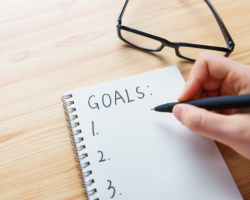 A person writing his goals on a notebook (Success Through Failure podcast episode 434: A Step-by-Step Goal Setting System That Works: A 20 Minute Masterclass for Clarity and Consistency)